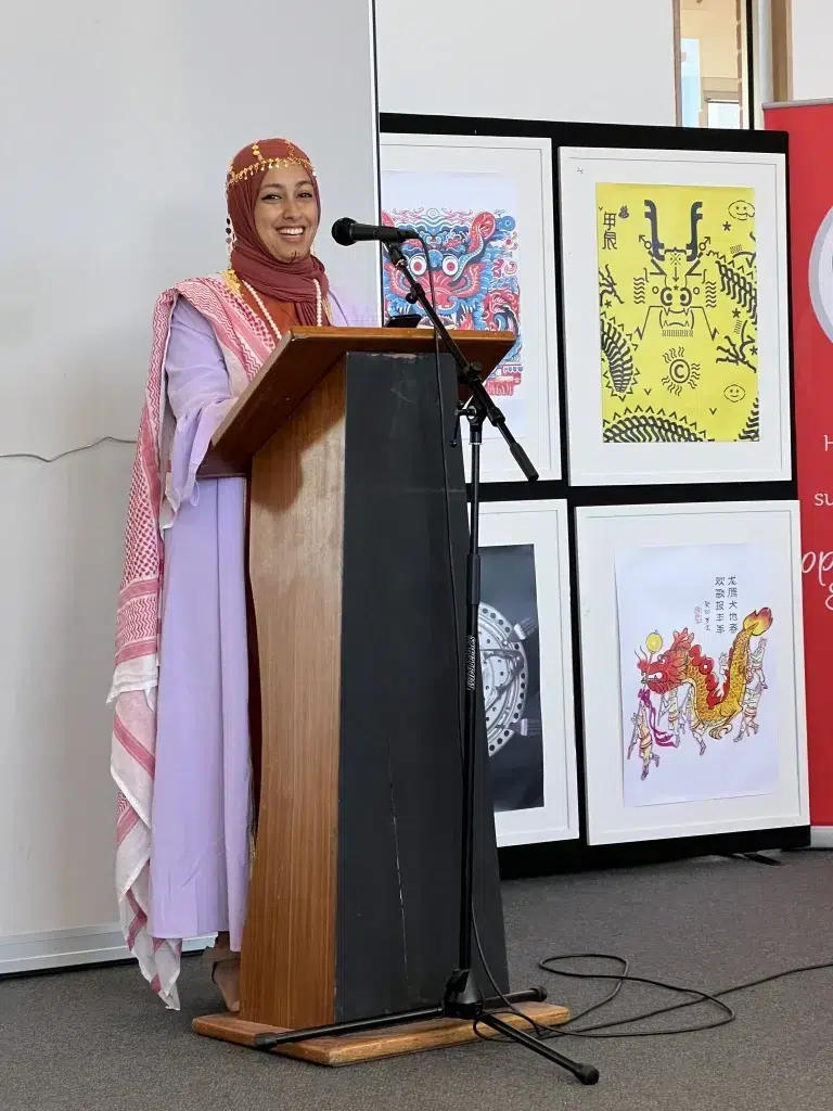 Woman in colourful attire speaks at podium.
