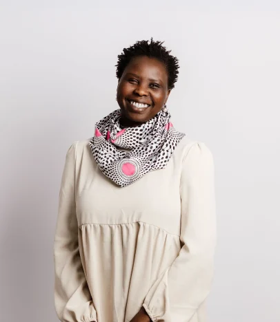 Smiling person wearing patterned scarf and cream dress.