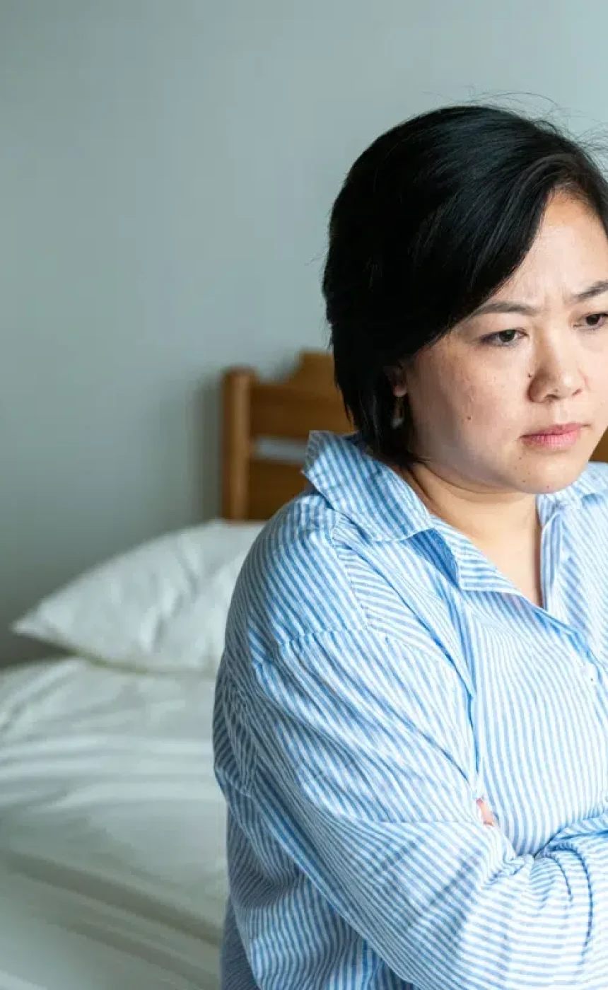 Upset couple sitting apart in bedroom.
